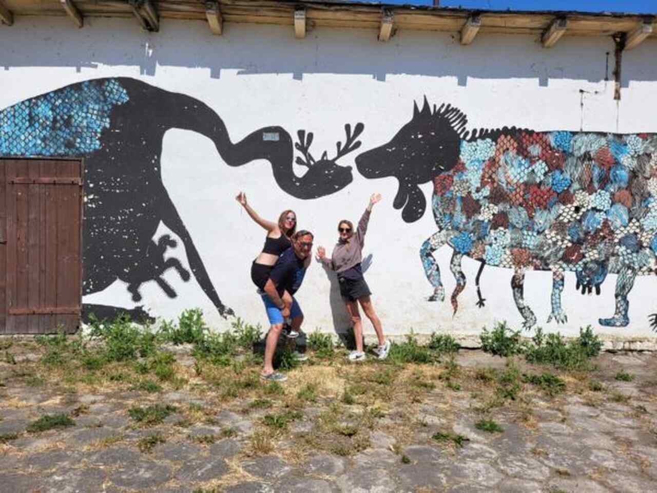 tata z dziećmi na tle murala na mazurach