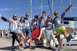 Ekipa uczestników na mazurskim rejsie, pozuje do zdjęcia na kei w Rynie.