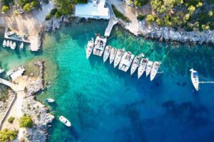 Rejs w Grecji – jachty i katamarany zacumowane w turkusowej zatoce