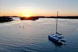 Katamaran na kotwicy w spokojnej zatoce w Chorwacji o zachodzie słońca – wieczór podczas tygodniowego rejsu